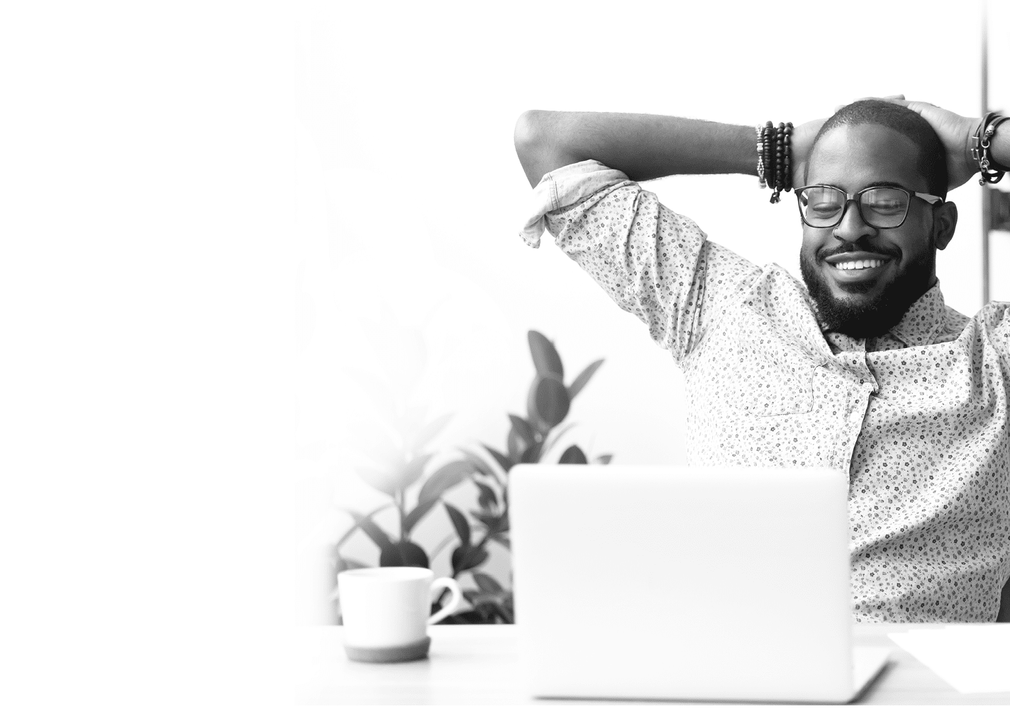 Smiling Afro-American businessman holding hands behind head sitting at office desk behind laptop  Happy black employee feeling no stress, relaxing, watching funny video after successful working