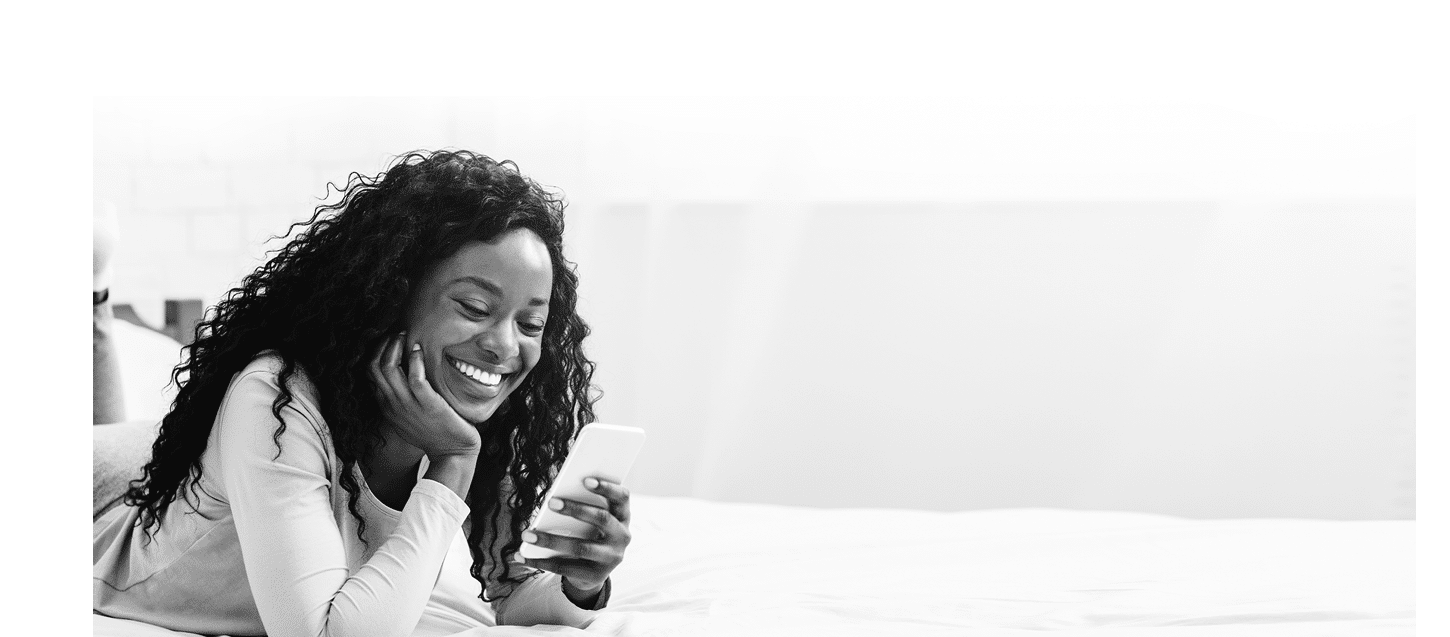 Black girl in love laying on bed and reading messages from her boyfriend, empty space